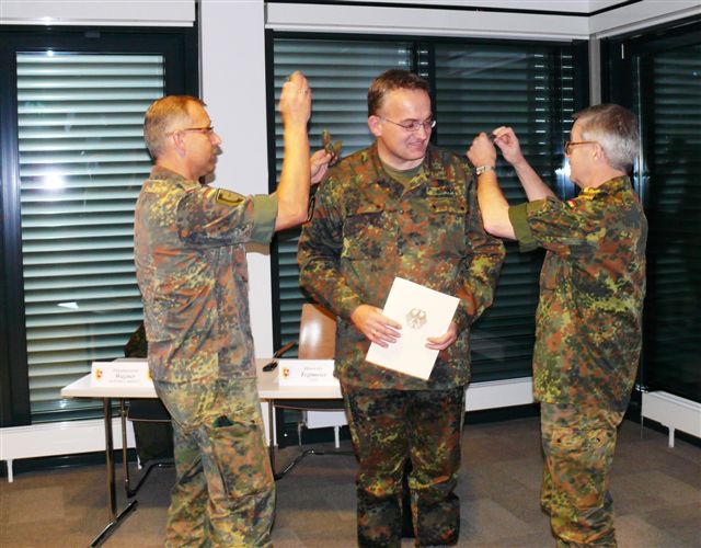 General Heinz Georg Wagner (re.) und Oberst Michael Tegtmeier, Chef des Stabes der 1. Panzerdivision, stecken Oberstleutnant Oliver Brandt neue Schulterklappen auf.